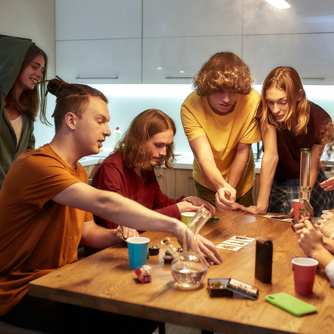 teens around a table playing card games while drinking and smoking